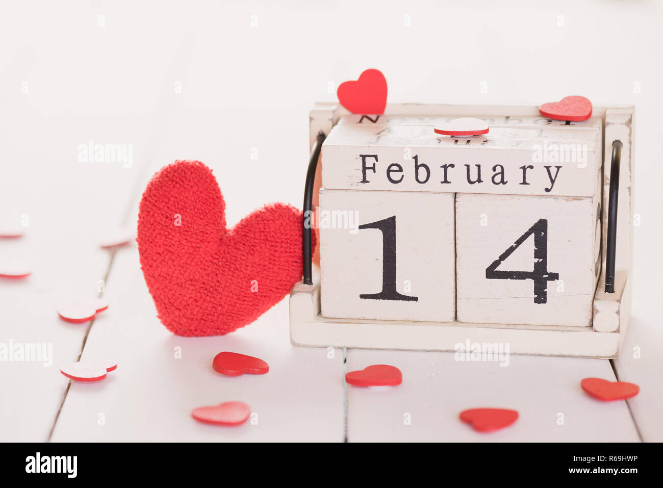 Il giorno di San Valentino del concetto. Febbraio 14 testo sul blocco di legno fatti a mano con cuore rosso su bianco sullo sfondo di legno. Foto Stock