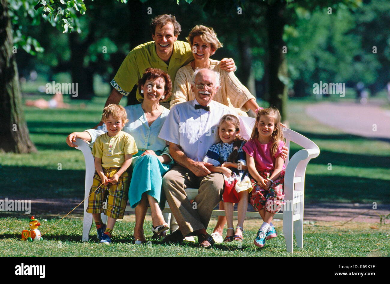 Ritratto, Familie sitzt auf einer Bank im Park, 7 Personen, 3 Generationen, Eltern, Grosseltern und 3 Kinder, 2 Maedchen, 1 Junge Foto Stock