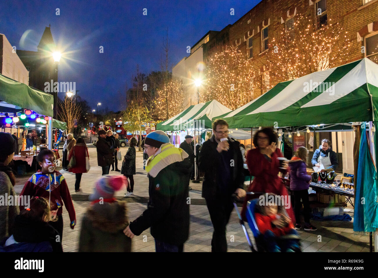 Notte tempo colpo di persone che passeggiano attraverso un mercato all'aperto illuminato con luci di Natale, Navigator Square, Archway, London, Regno Unito Foto Stock