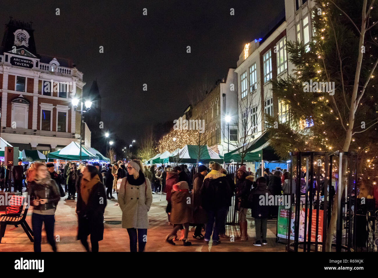 Notte tempo colpo di persone che passeggiano attraverso un mercato all'aperto illuminato con luci di Natale, Navigator Square, Archway, London, Regno Unito Foto Stock