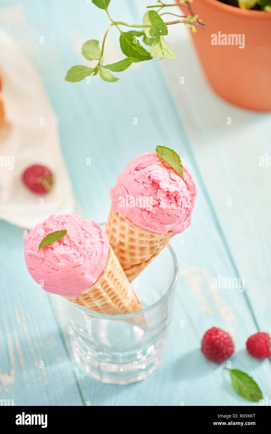 In casa gelato al lampone in cialda coni in legno rustico sfondo, il fuoco selettivo. Orario estivo Foto Stock