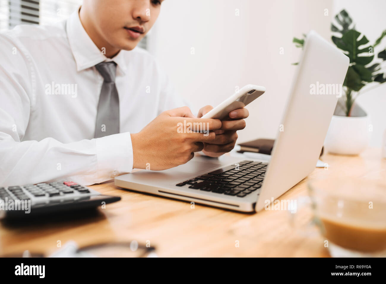 Business man occupato a lavorare sul computer portatile e utilizzando mobile smart phone in ufficio moderno, vicino. Processo di lavoro concept Foto Stock