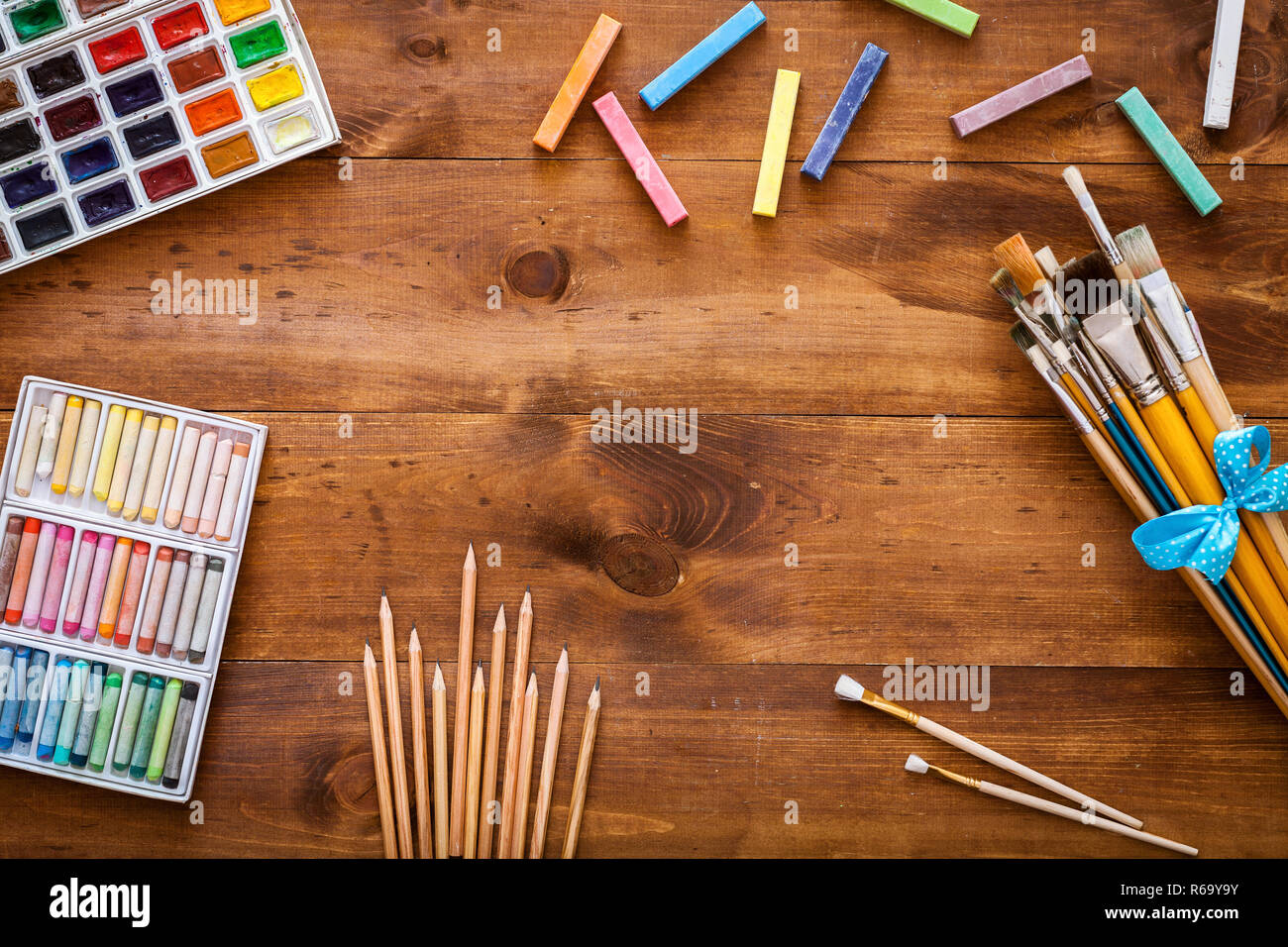 Arte creativa degli accessori di lavoro fornisce strumenti impostata sul banco disordinato, pennelli, paintbox acquerelli pastelli matite in legno marrone backgroun artistica Foto Stock