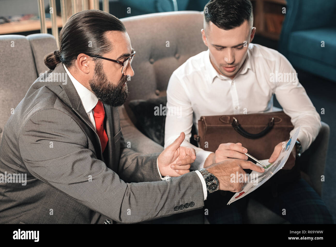 Il boss barbuto spiegando momenti di lavoro al suo giovane partecipante Foto Stock