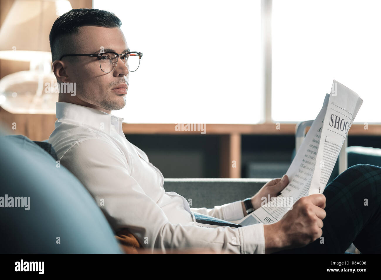 Giovani promettenti economista indossando occhiali lettura notizie finanziarie Foto Stock