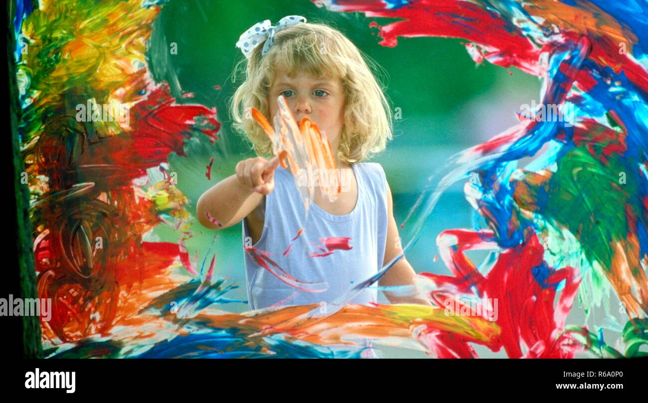 Ritratto, bionde Maedchen, 5 Jahre, bemalt Fensterscheibe mit bunten Fingerfarben Foto Stock