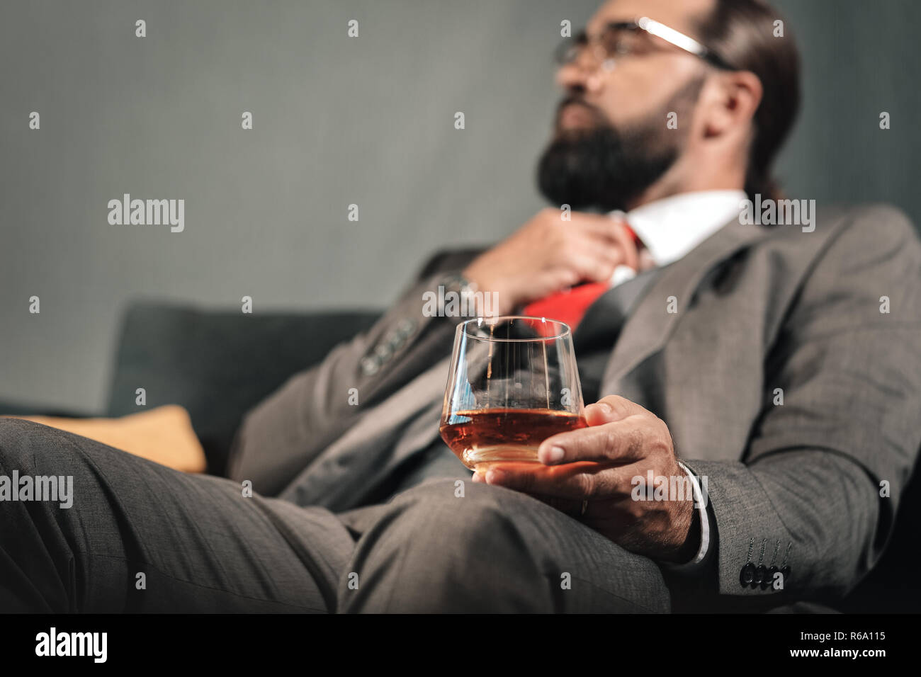 Imprenditore barbuto avente esaurimento nervoso bere cognac Foto Stock