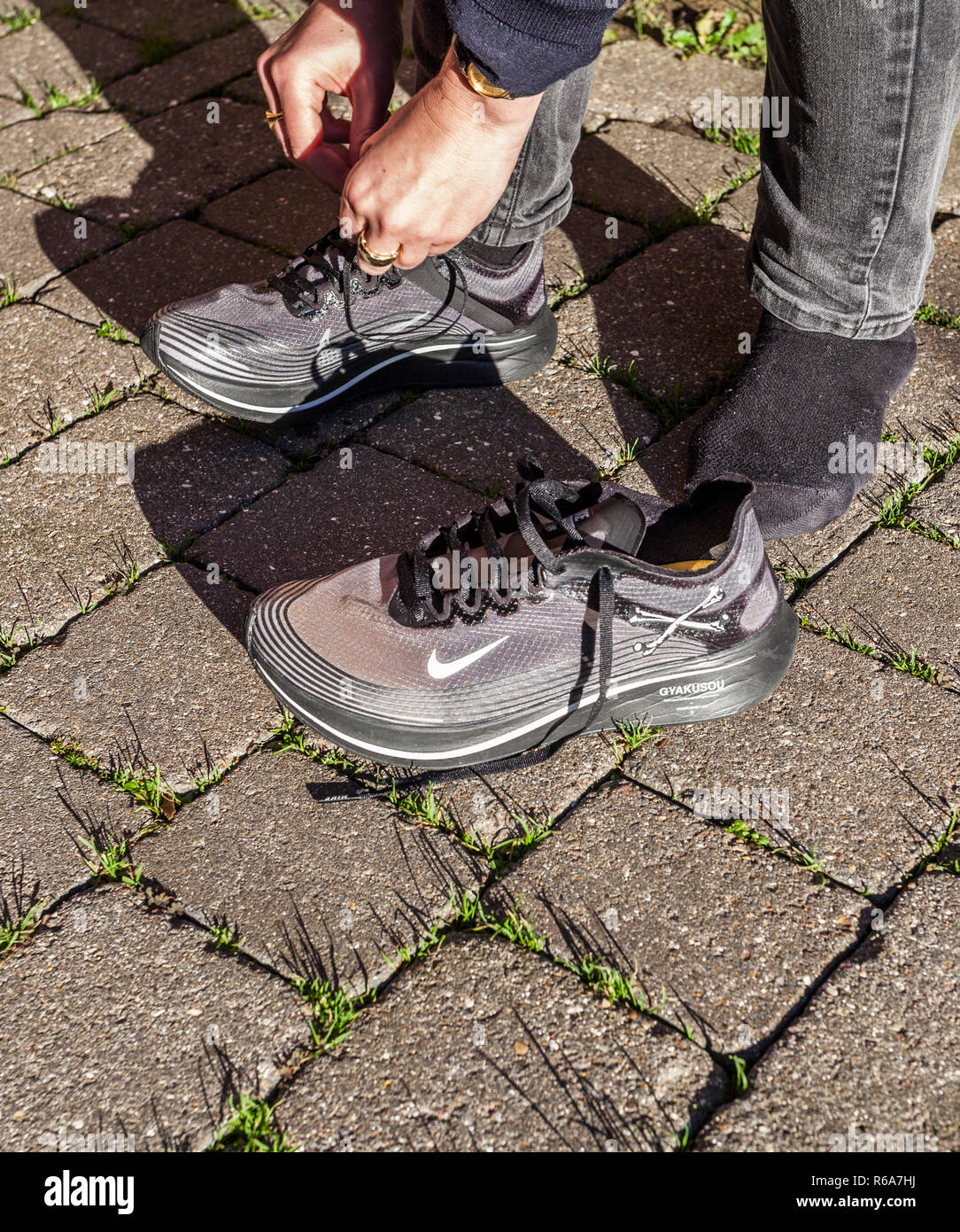 Una donna di occupare il suo laces su una coppia di grigio Nike Zoom Fly  Gyakusou formatori Foto stock - Alamy