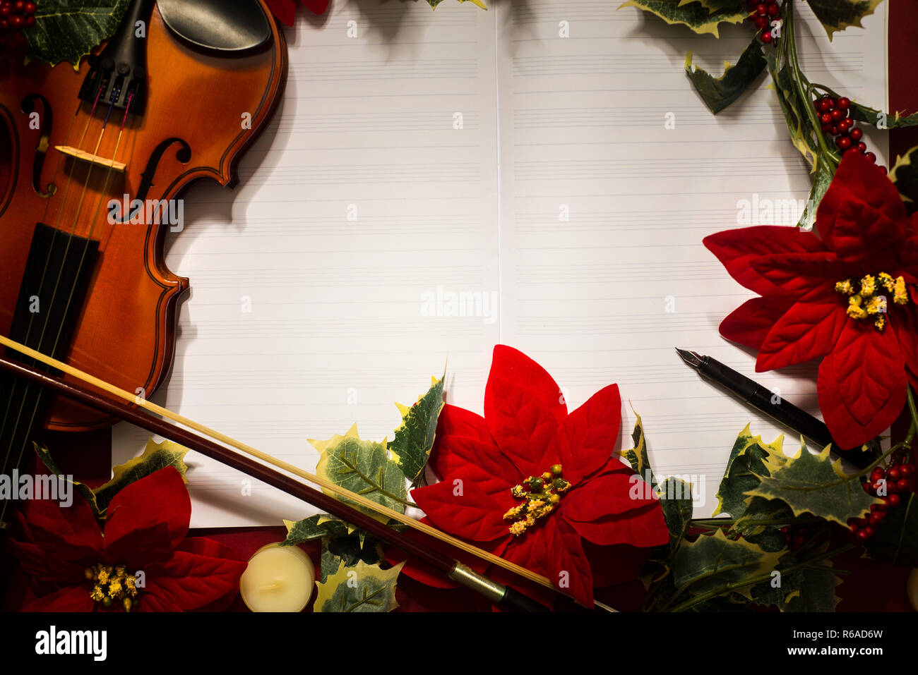 Il violino e la musica aperta manoscritto su sfondo rosso. Concetto di natale Foto Stock