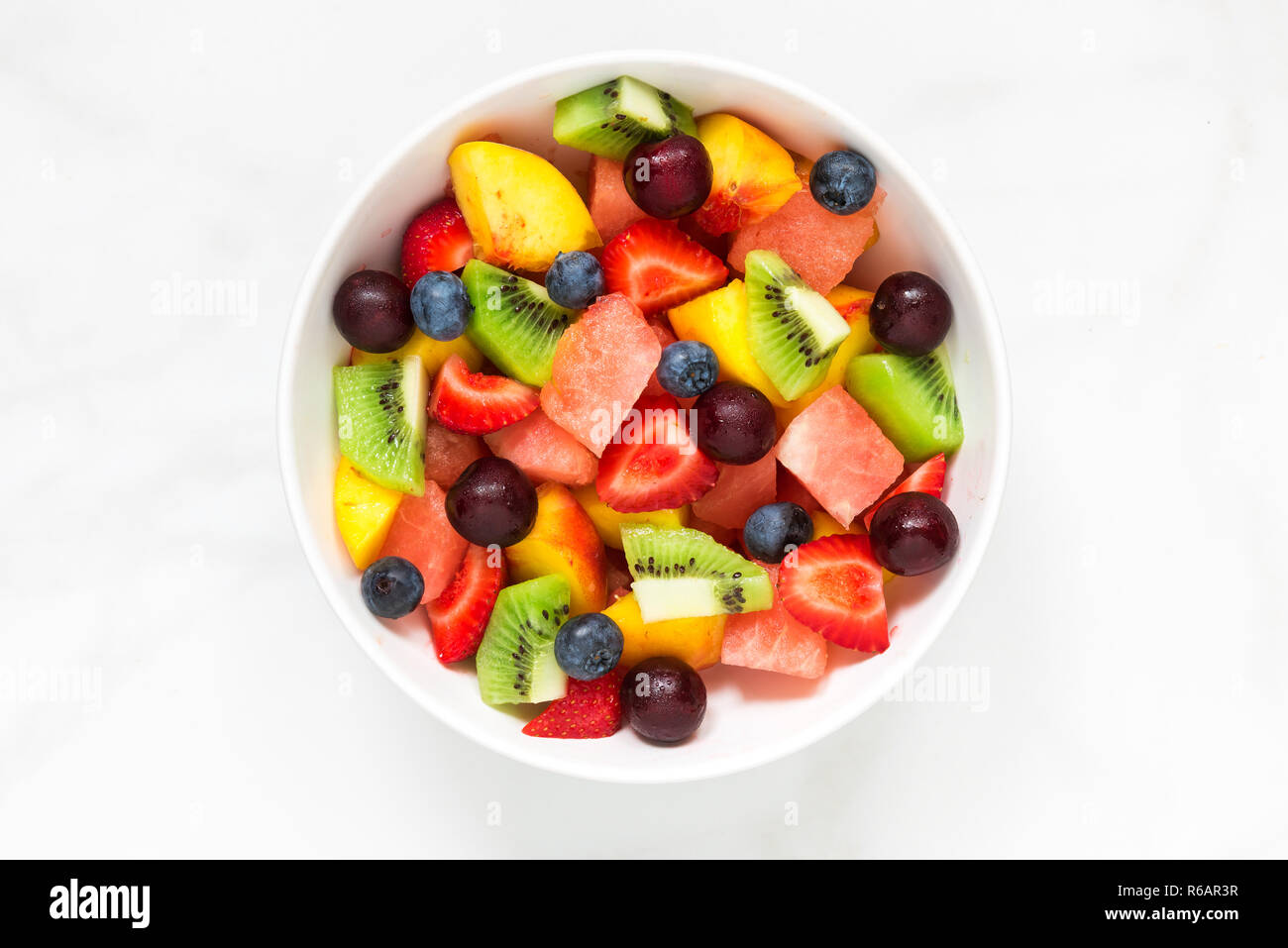 Ciotola di sana insalata di frutta fresca su marmo bianco dello sfondo. cibo sano. vista dall'alto. Foto Stock