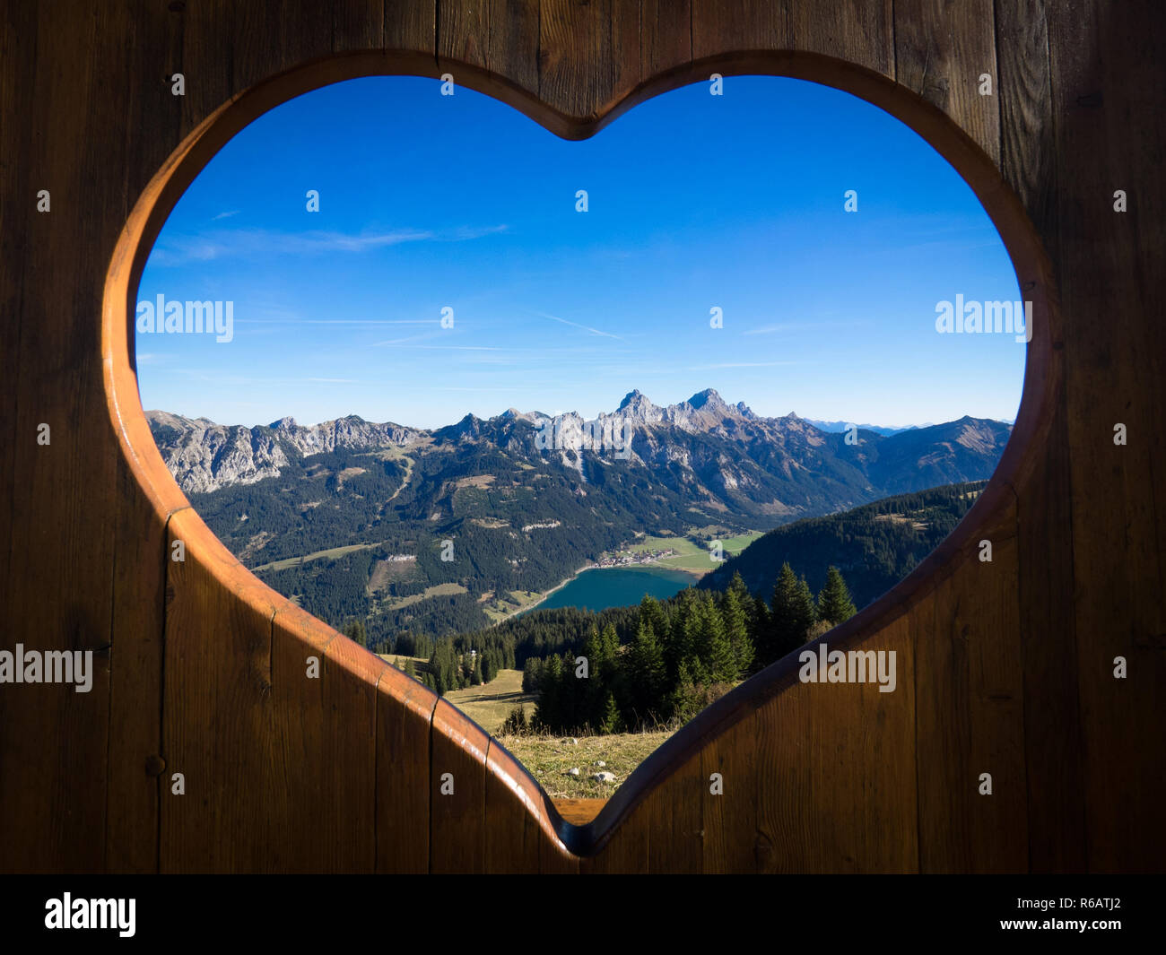 Tannheimer Tal panorama con vista sul lago Haldensee visto attraverso un cuore di legno Foto Stock