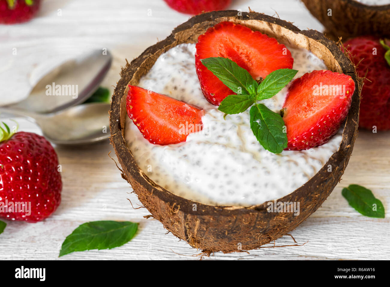 Chia pudding con fragole fresche e menta nella tazza di cocco con cucchiai. Colazione sana. close up Foto Stock