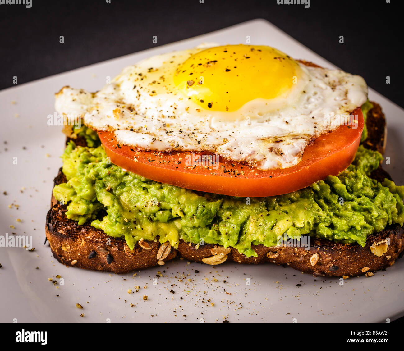 Avocado Toast con affettato tomator e soleggiato lato fino a uovo fritto. Foto Stock