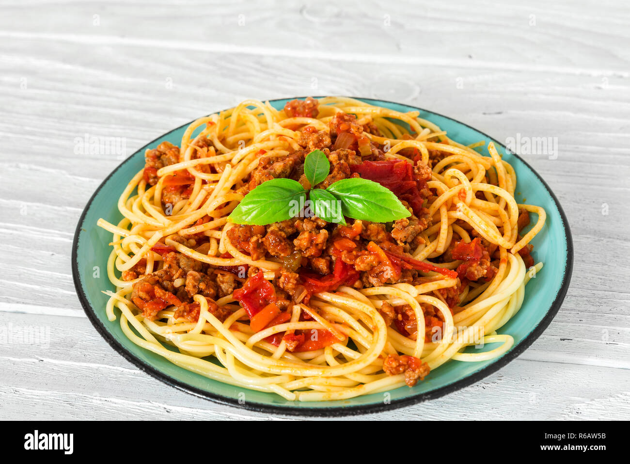Spaghetti alla bolognese su una piastra blu su bianco tavolo in legno. cibo sano. close up. pasta italiana Foto Stock