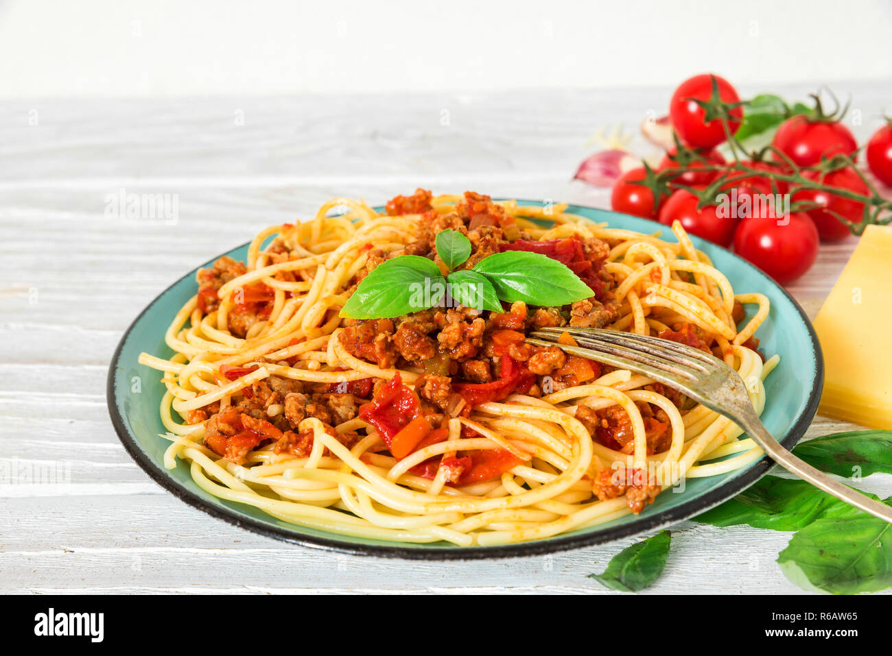 Pasta spaghetti alla bolognese su una piastra blu con la forcella su bianco tavolo in legno. cibo sano. close up Foto Stock