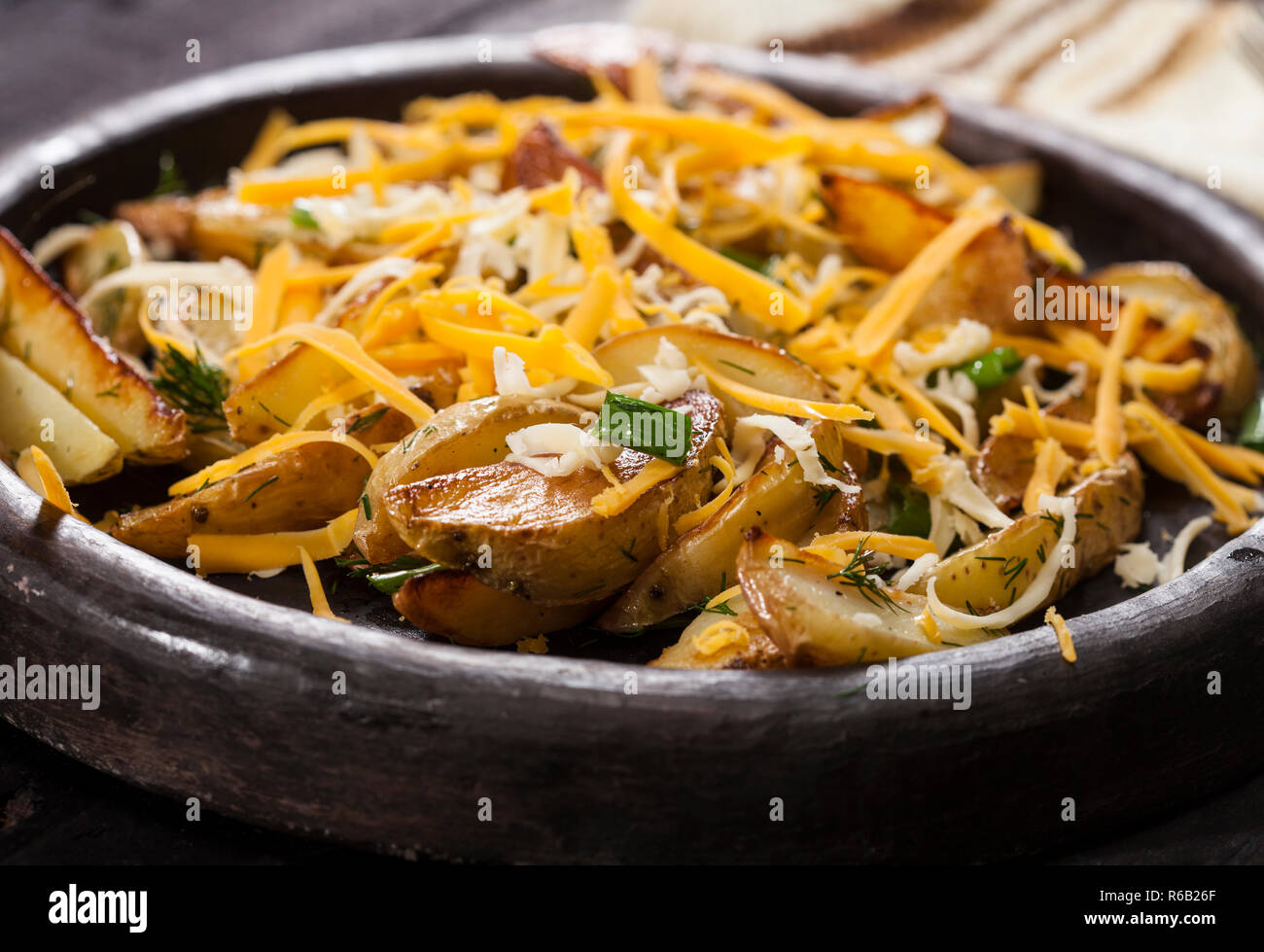 Patate al forno cunei con formaggio, erba cipollina e aneto. In casa vegetale organico vegetariano vegano Spicchi di patate snack alimentare. Foto Stock