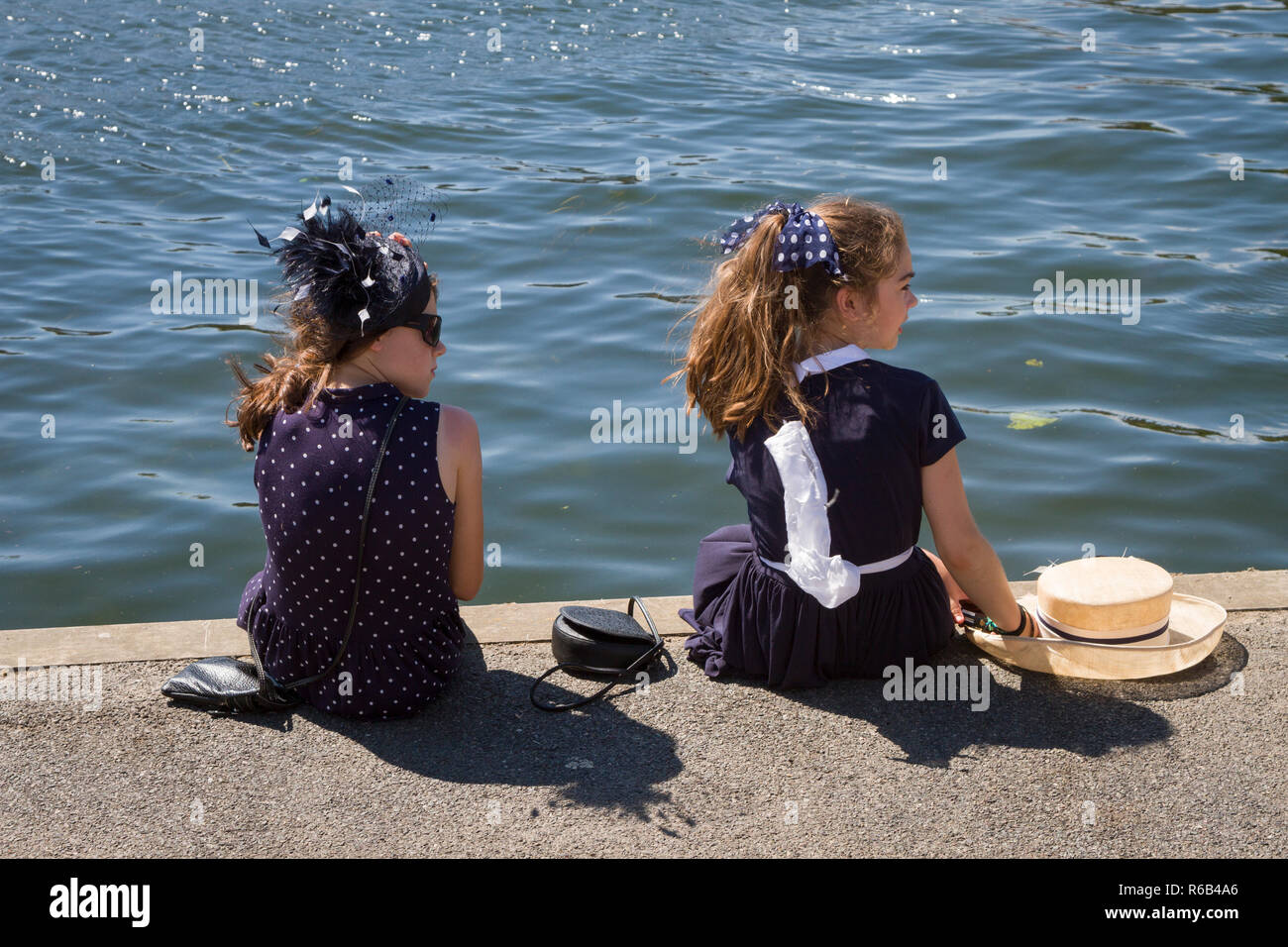 Due ragazze vestite in modo intelligente si siedono sul lato del fiume alla Henley Royal Regatta Foto Stock