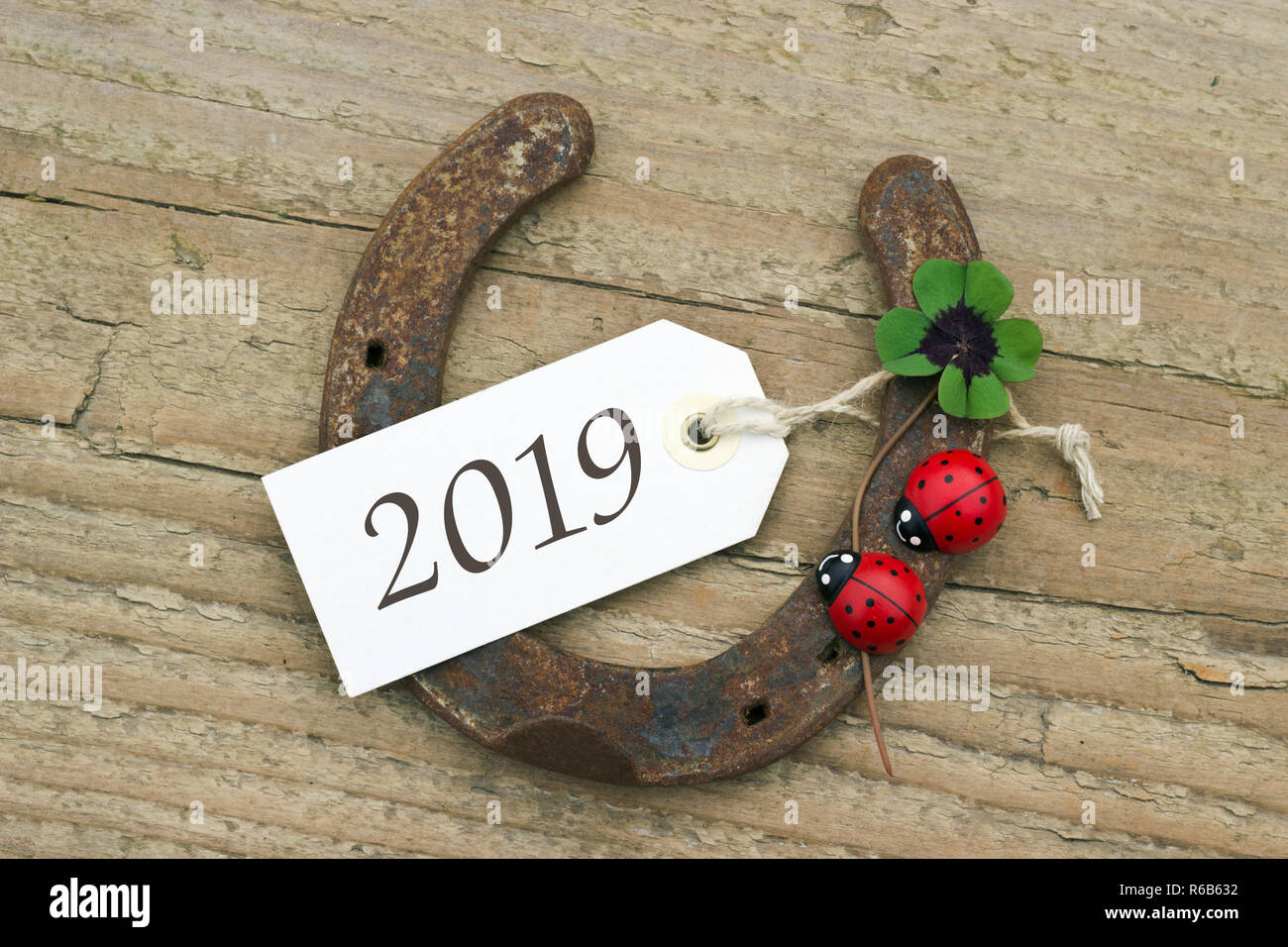 Nuovo anno di carta con il ferro di cavallo, Leafed trifoglio e ladybugs su sfondo di legno Foto Stock