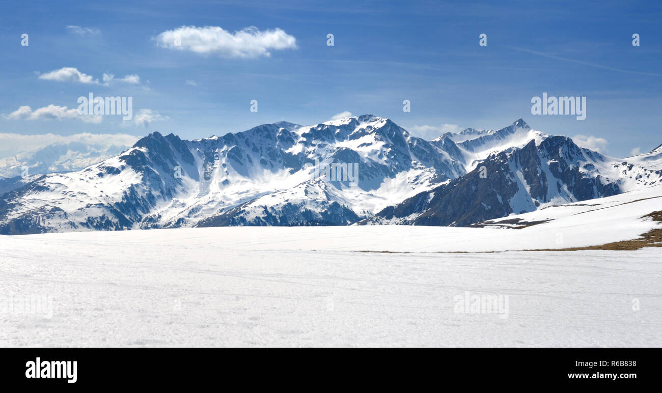 Vista sul picco alpino coevred montagne con la neve sotto il cielo blu Foto Stock