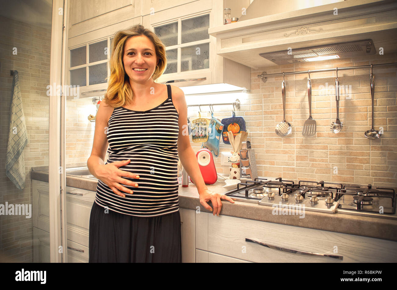 Ci aspettavamo una donna incinta pancia mano moderna cucina -dieta maternità Foto Stock
