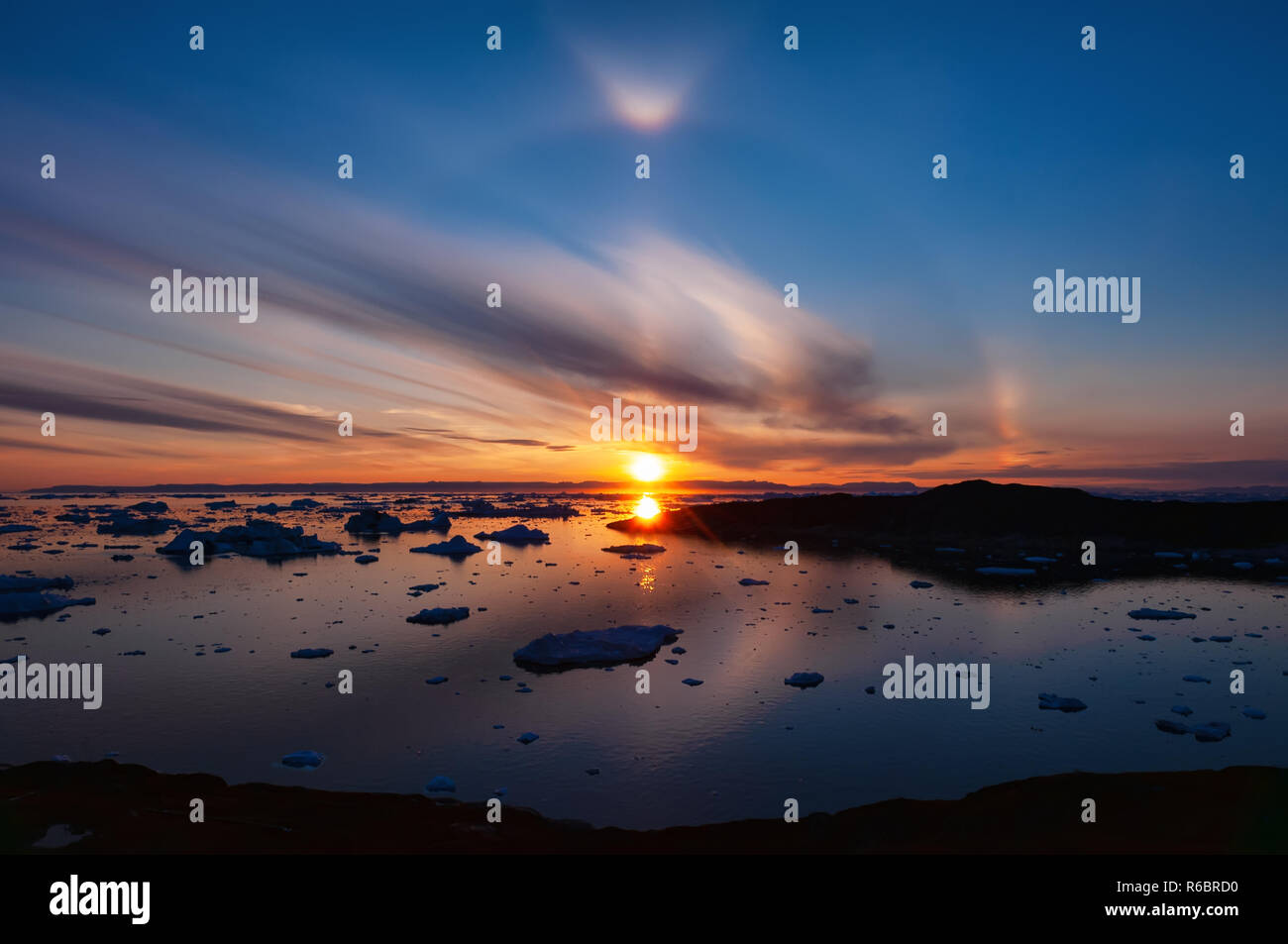 Tramonto sulla baia di Disko in Groenlandia circolare con effetto di alone. Alone è il nome di una famiglia di fenomeni ottici prodotta dalla luce solare Foto Stock