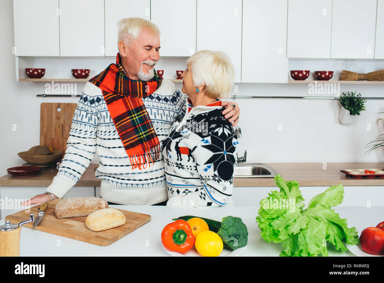 Coppia senior di cucina mangiare sano e sorridente ad ogni altro in cucina Foto Stock