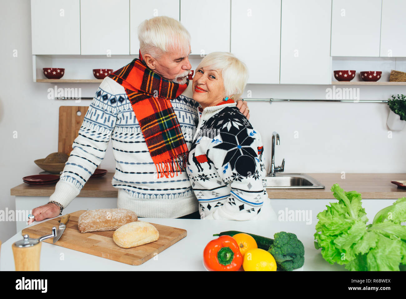 Coppia senior di cucina mangiare sano e sorridente ad ogni altro in cucina Foto Stock