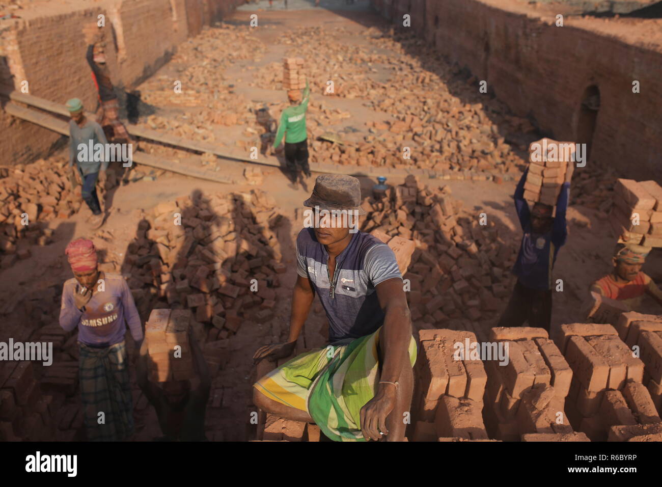 Fatiche stanno lavorando a un campo di mattoni con condizioni malsane a Dhaka, nel Bangladesh. Fatiche compresi i bambini lavorano in campi di mattoni fino al tramonto con condizione non sana come il salario non rispondono a standard minimo. Bengalese ha classificato in più rapida crescita paese al mondo come urbanizzazione in rapido aumento. Nonostante di mattone è la chiave i materiali per costruire la struttura di un edificio come grande numero di cantieri di mattoni ha avuto luogo in terre agricole riducendo la produzione agricola. La maggior parte dei cantieri di mattoni utilizzare boschi, carbone per bruciare mattoni crudi come CO2 Emissioni di gas. Foto Stock