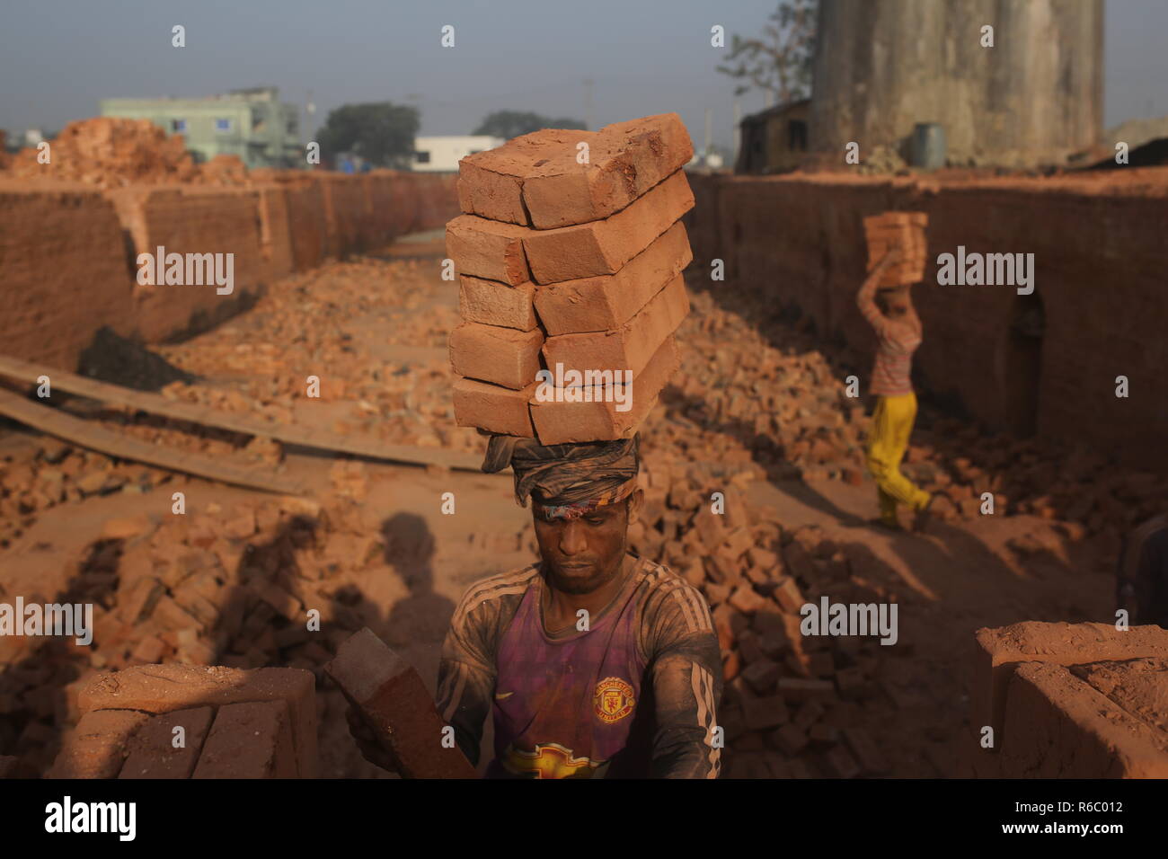 Fatiche stanno lavorando a un campo di mattoni con condizioni malsane a Dhaka, nel Bangladesh. Fatiche compresi i bambini lavorano in campi di mattoni fino al tramonto con condizione non sana come il salario non rispondono a standard minimo. Bengalese ha classificato in più rapida crescita paese al mondo come urbanizzazione in rapido aumento. Nonostante di mattone è la chiave i materiali per costruire la struttura di un edificio come grande numero di cantieri di mattoni ha avuto luogo in terre agricole riducendo la produzione agricola. La maggior parte dei cantieri di mattoni utilizzare boschi, carbone per bruciare mattoni crudi come CO2 Emissioni di gas. Foto Stock