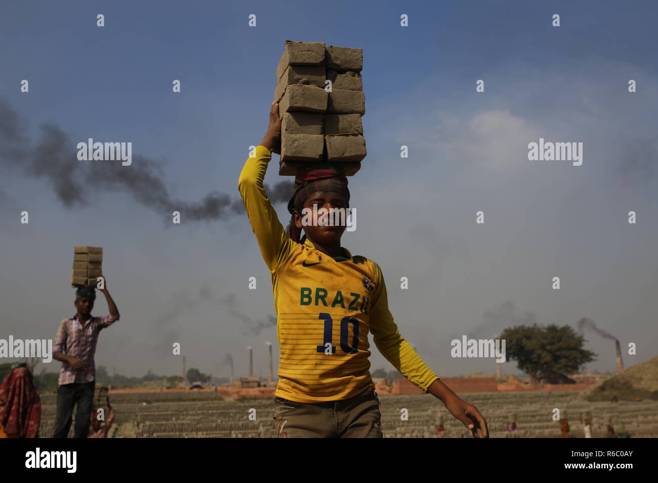 I bambini stanno lavorando a un campo di mattoni con condizioni malsane a Dhaka, nel Bangladesh. Fatiche compresi i bambini lavorano in campi di mattoni fino al tramonto con condizione non sana come il salario non rispondono a standard minimo. Bengalese ha classificato in più rapida crescita paese al mondo come urbanizzazione in rapido aumento. Nonostante di mattone è la chiave i materiali per costruire la struttura di un edificio come grande numero di cantieri di mattoni ha avuto luogo in terre agricole riducendo la produzione agricola. La maggior parte dei cantieri di mattoni utilizzare boschi, carbone per bruciare mattoni crudi come CO2 Emissioni di gas. Foto Stock