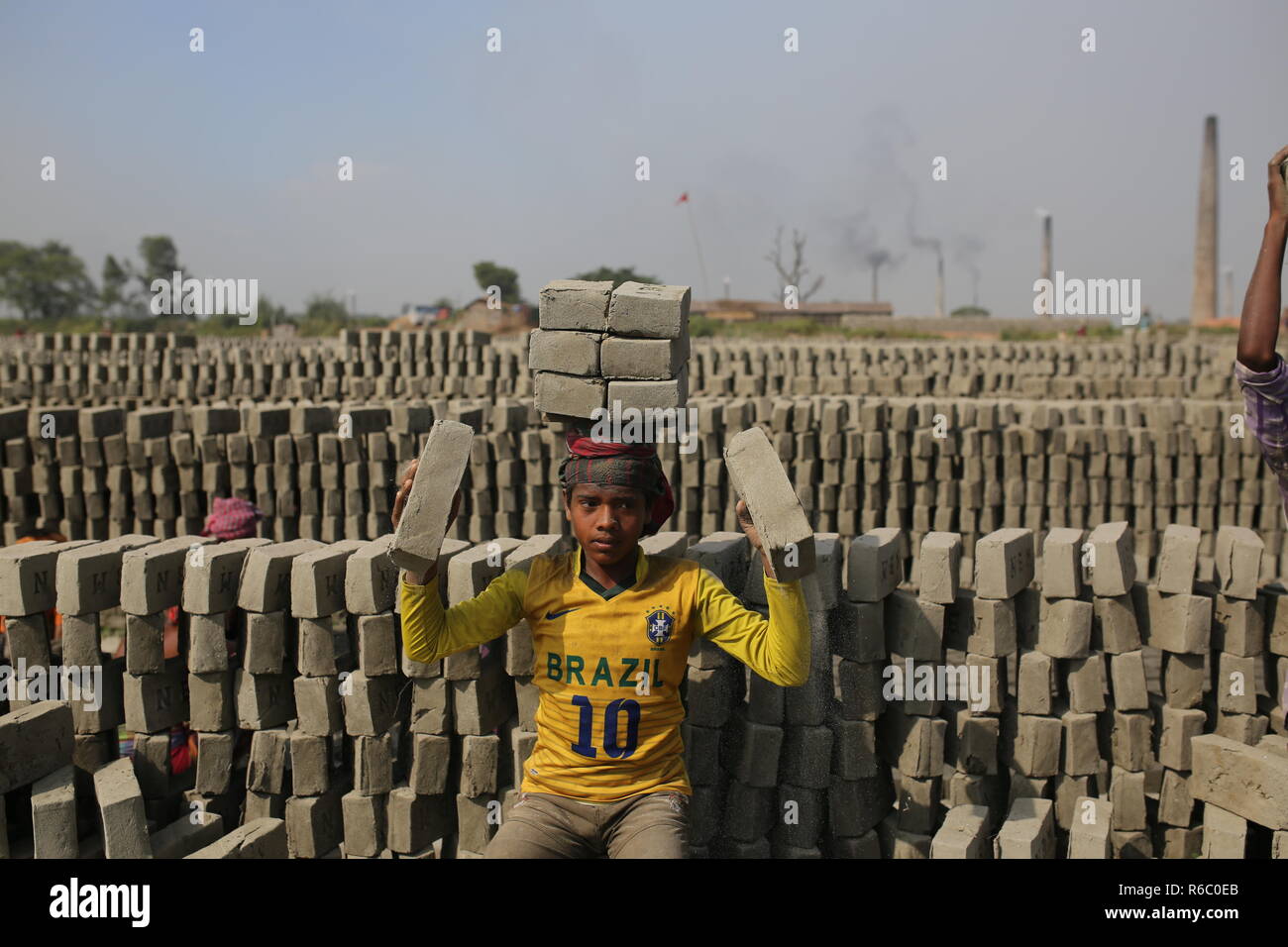 I bambini stanno lavorando a un campo di mattoni con condizioni malsane a Dhaka, nel Bangladesh. Fatiche compresi i bambini lavorano in campi di mattoni fino al tramonto con condizione non sana come il salario non rispondono a standard minimo. Bengalese ha classificato in più rapida crescita paese al mondo come urbanizzazione in rapido aumento. Nonostante di mattone è la chiave i materiali per costruire la struttura di un edificio come grande numero di cantieri di mattoni ha avuto luogo in terre agricole riducendo la produzione agricola. La maggior parte dei cantieri di mattoni utilizzare boschi, carbone per bruciare mattoni crudi come CO2 Emissioni di gas. Foto Stock