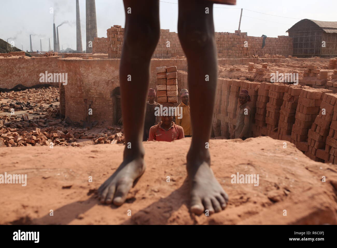 Fatiche stanno lavorando a un campo di mattoni con condizioni malsane a Dhaka, nel Bangladesh. Fatiche compresi i bambini lavorano in campi di mattoni fino al tramonto con condizione non sana come il salario non rispondono a standard minimo. Bengalese ha classificato in più rapida crescita paese al mondo come urbanizzazione in rapido aumento. Nonostante di mattone è la chiave i materiali per costruire la struttura di un edificio come grande numero di cantieri di mattoni ha avuto luogo in terre agricole riducendo la produzione agricola. La maggior parte dei cantieri di mattoni utilizzare boschi, carbone per bruciare mattoni crudi come CO2 Emissioni di gas. Foto Stock