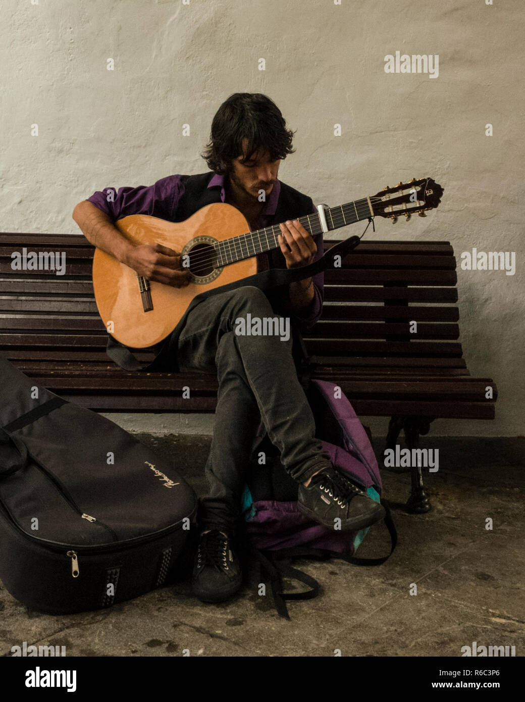 Santa Cruz. La Palma, Spagna. Ritratto di un musicista locale praticando la sua chitarra acustica su un banco di pubblico. Fotografia scattata per le strade di Santa Cruz. Foto Stock