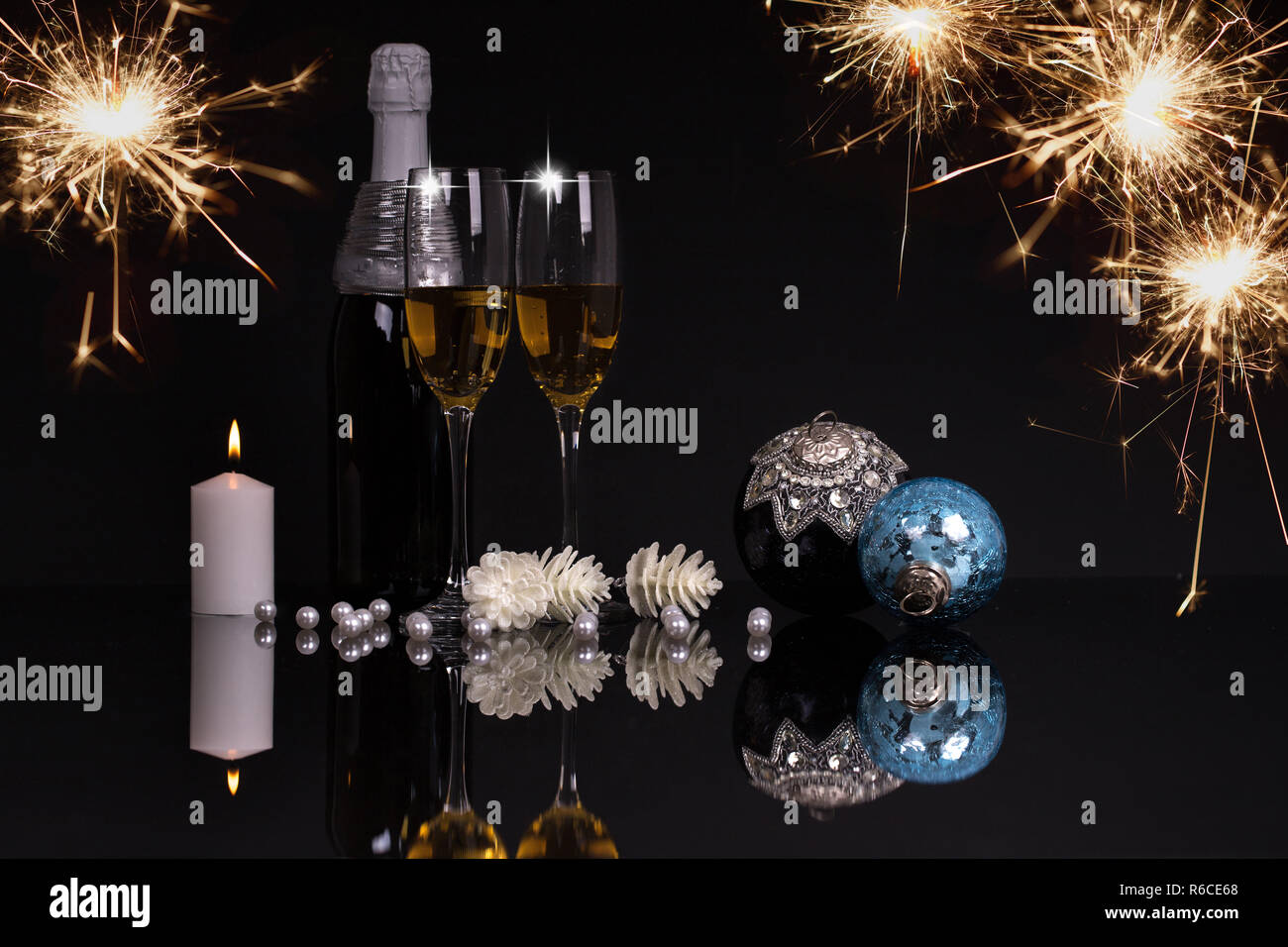 Due bicchieri di vino con champagne, candele e Addobbi Natale su uno sfondo nero con la riflessione. Copia dello spazio. Buon Natale e Felice Anno Nuovo Foto Stock
