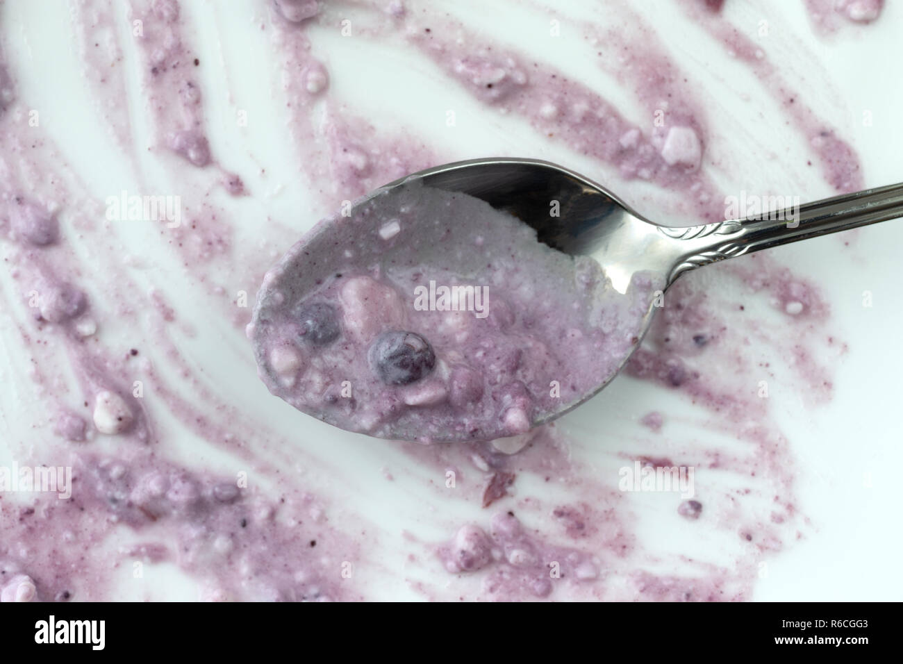 Vista aerea di un pasto finito di mirtilli e ricotta su una piastra bianca con un cucchiaio. Foto Stock