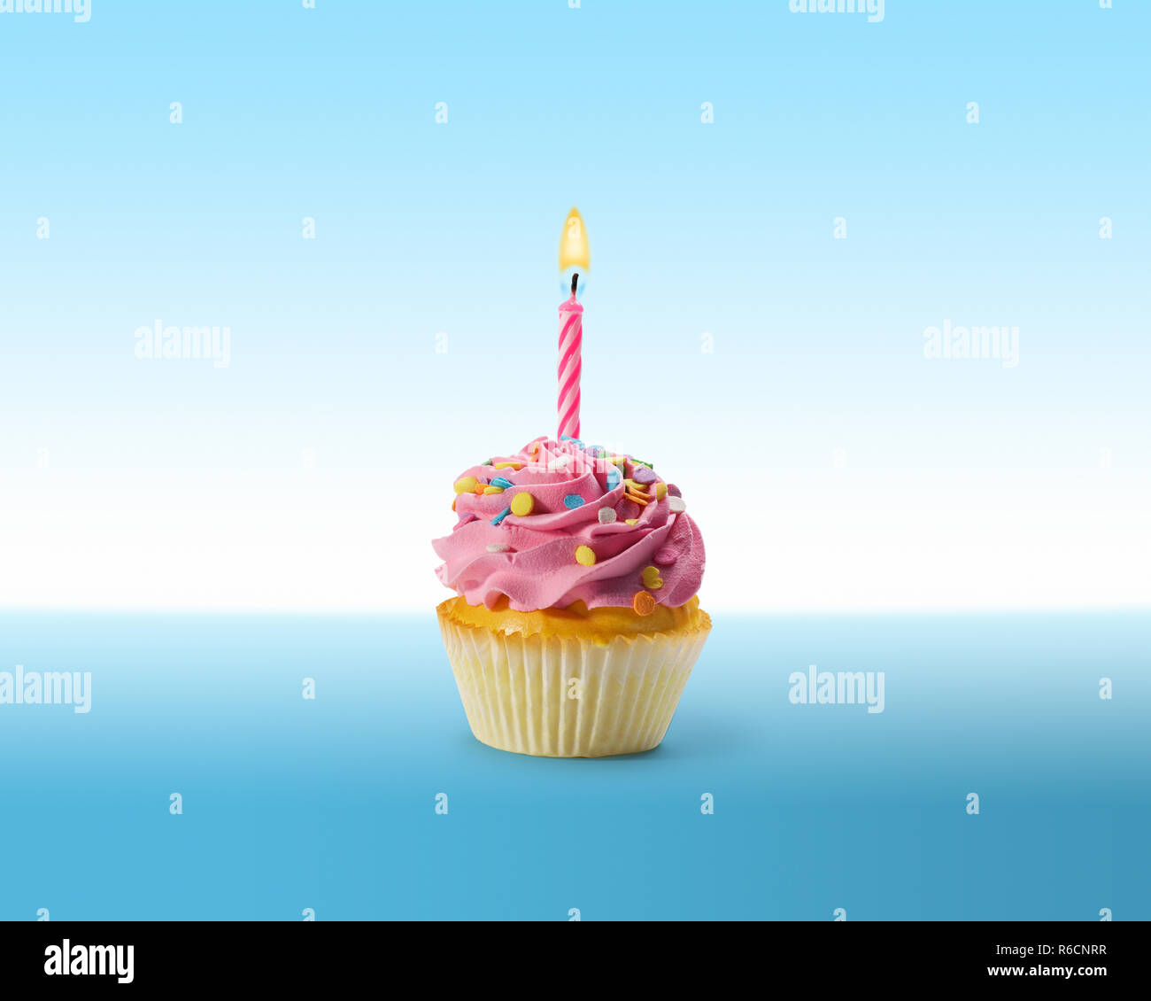 Compleanno cupcake con la glassa e una candela accesa su una superficie di colore blu Foto Stock