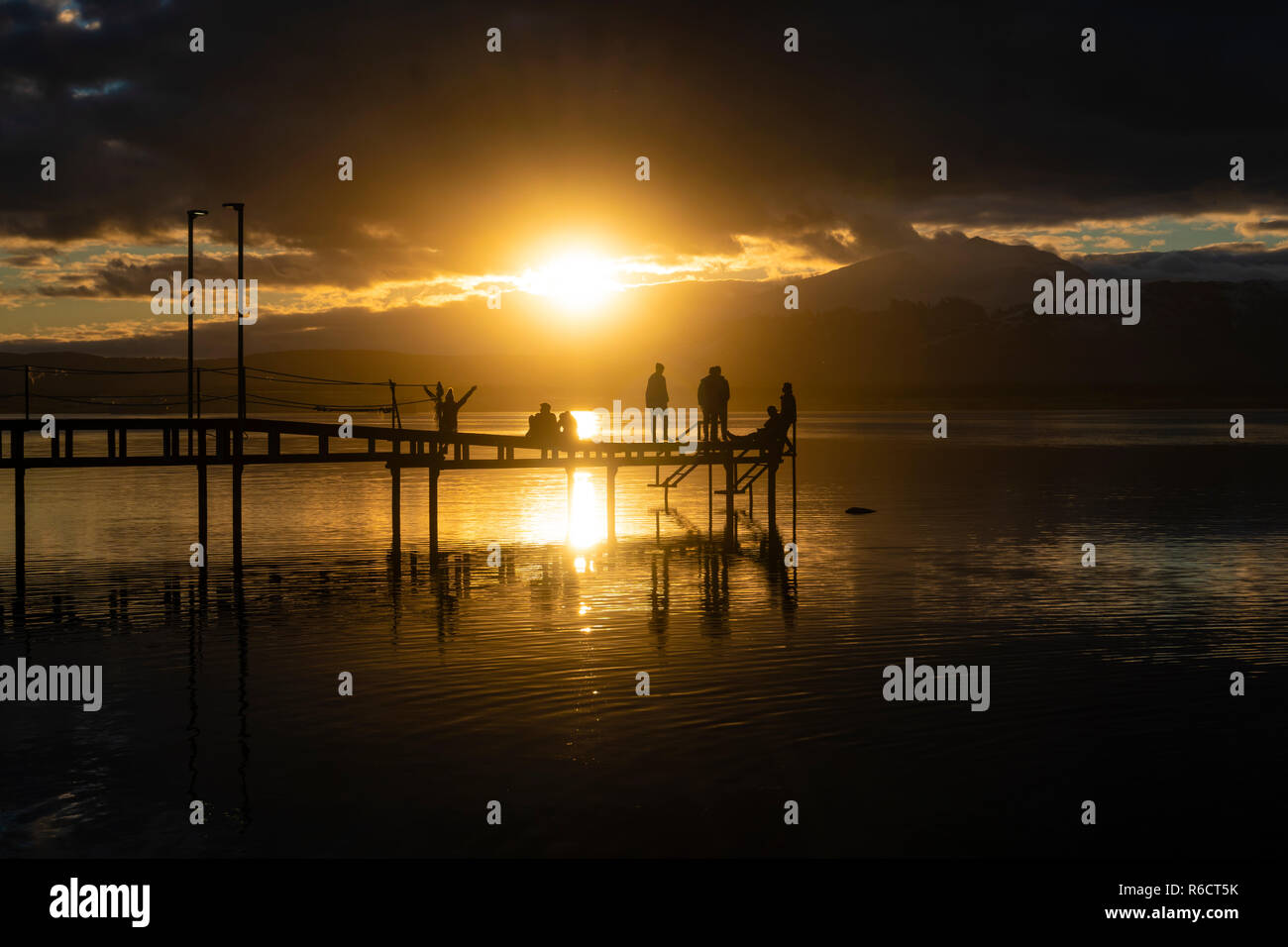 Le persone in un momento di relax a un molo durante il tramonto Foto Stock