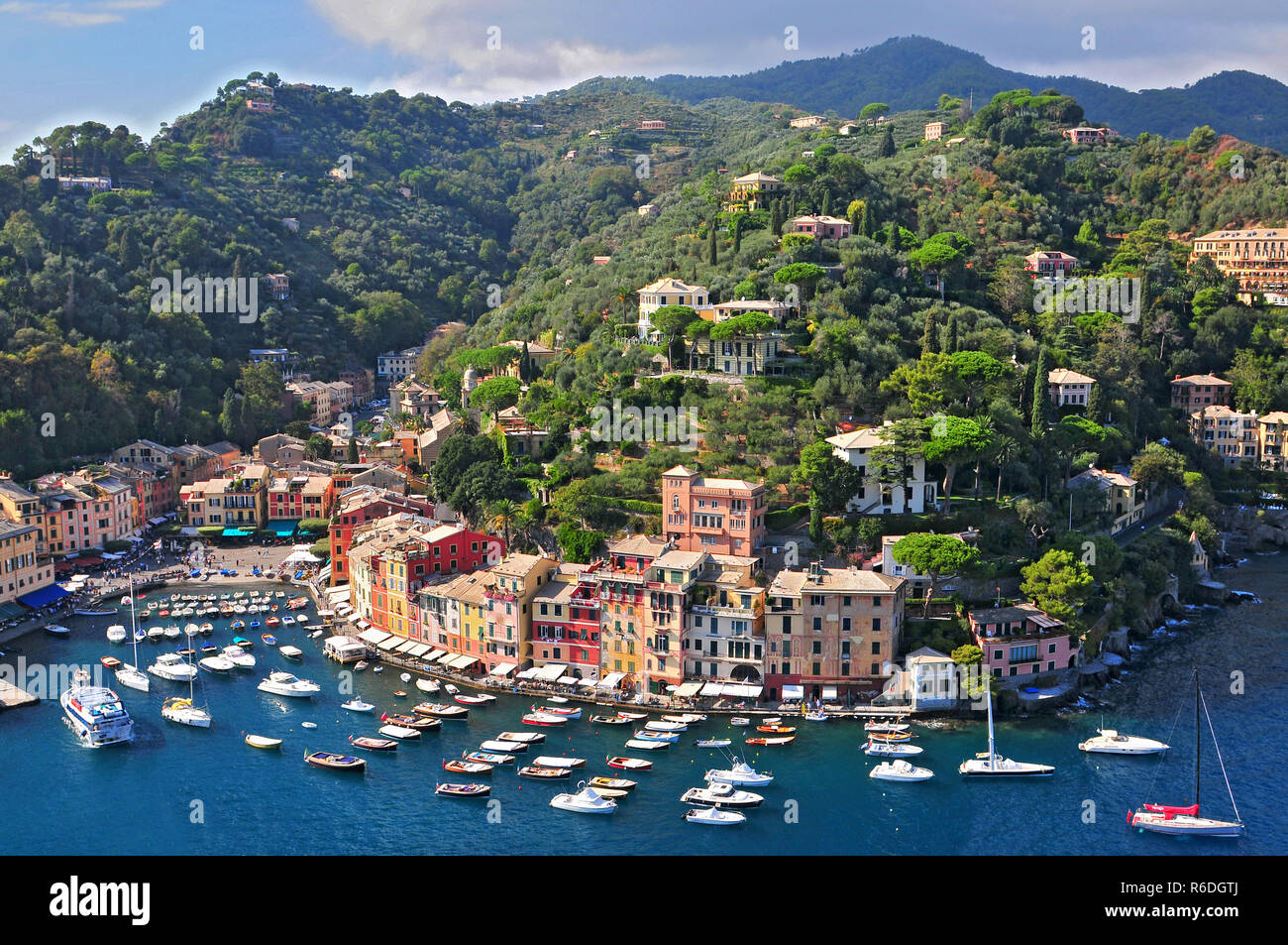 Liguria Portofino vista del porto con barche ormeggiate e le case dai colori pastello di rivestimento del Bay con alberi sulle colline dietro Foto Stock