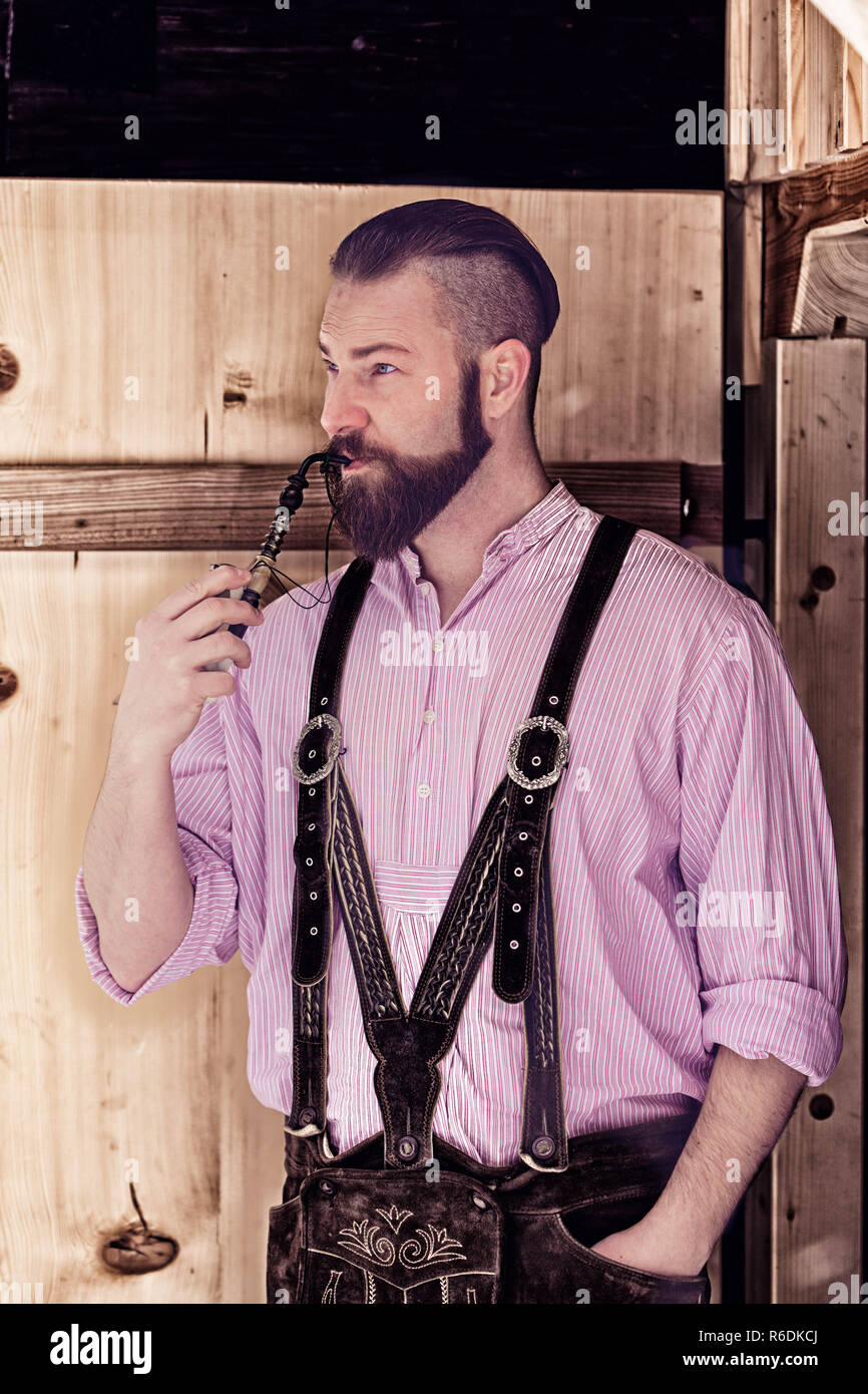 Bavarian giovane uomo in pantaloni di pelle e capelli eleganti fumare un  tubo Foto stock - Alamy