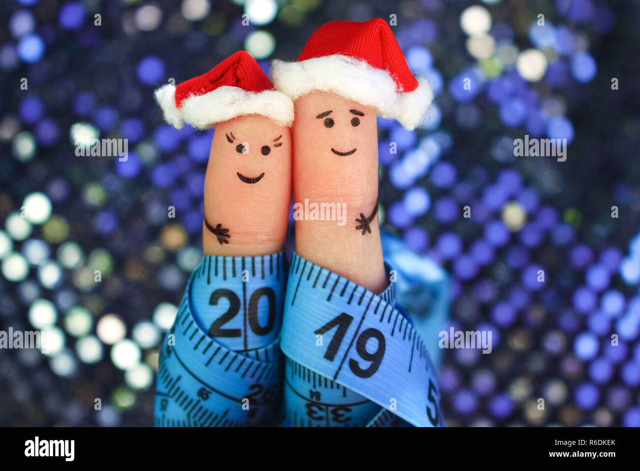 Dita di arte giovane festeggia il Natale. Concetto di uomo e di donna che ride nel nuovo anno cappelli. Nastro di misurazione è scritto 2019. Tonica immagine. Foto Stock