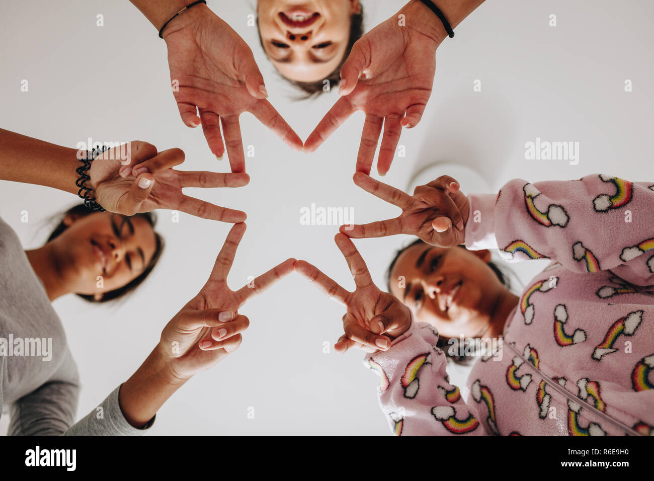 Basso angolo vista di tre ragazze facendo una forma a stella con le loro dita. Ragazze sorridenti divertirsi a sleepover giocare. Foto Stock