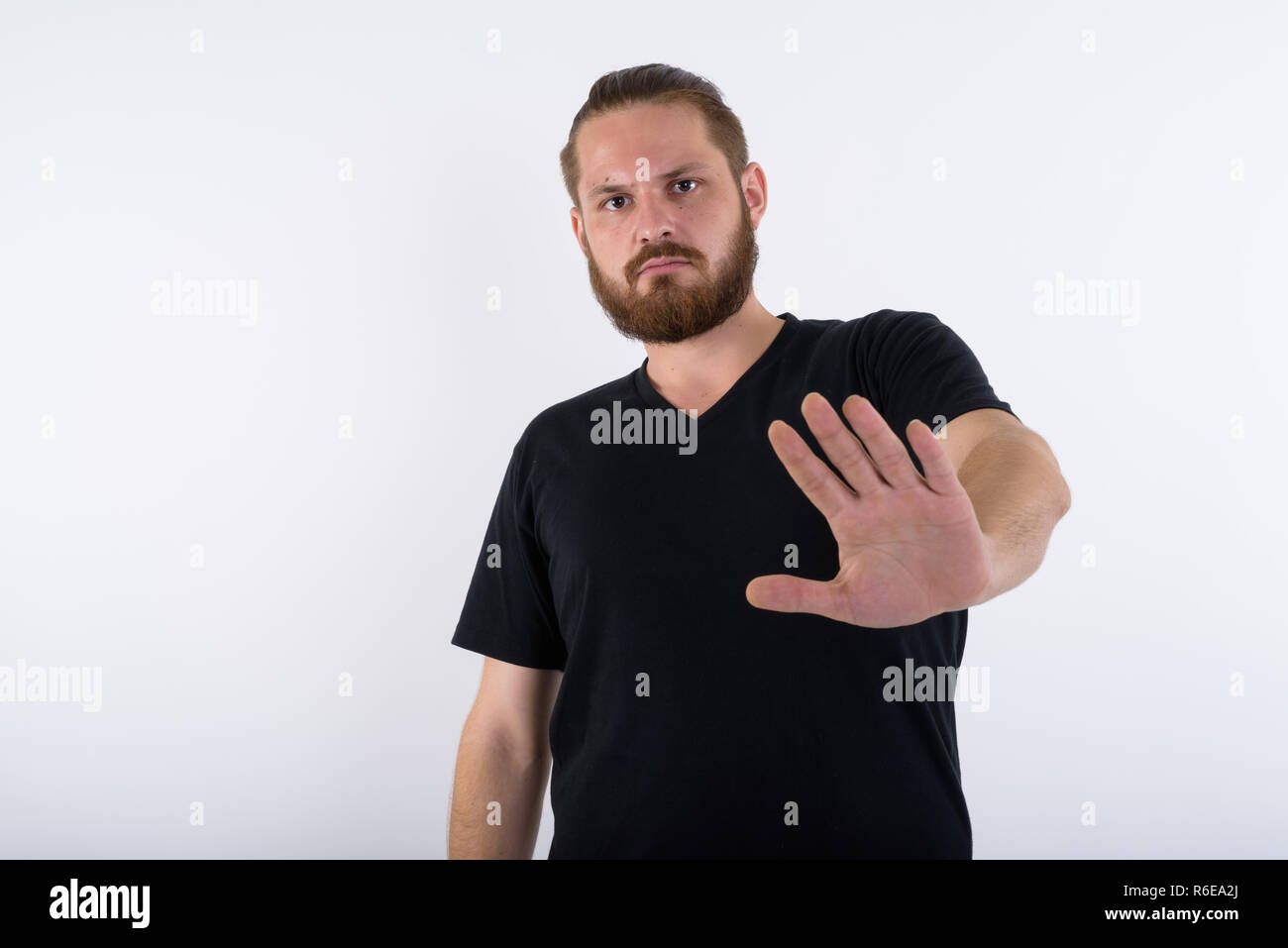 Studio shot del giovane uomo barbuto che mostra la mano di arresto nuovo gesto Foto Stock