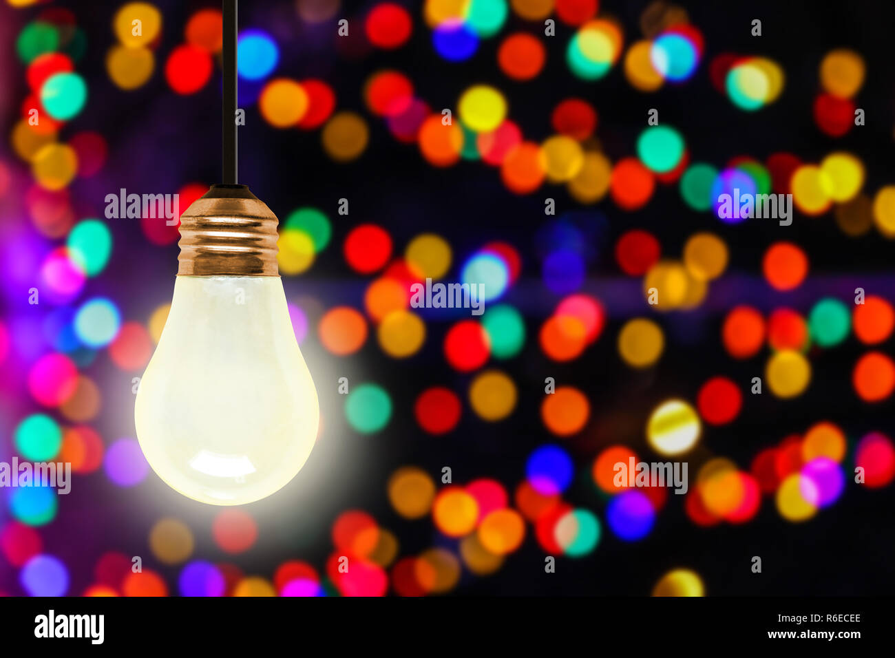 Luce di illuminazione lampadina appesa con colorati sfocate luci di Natale bokeh effetto copia e spazio. Foto Stock