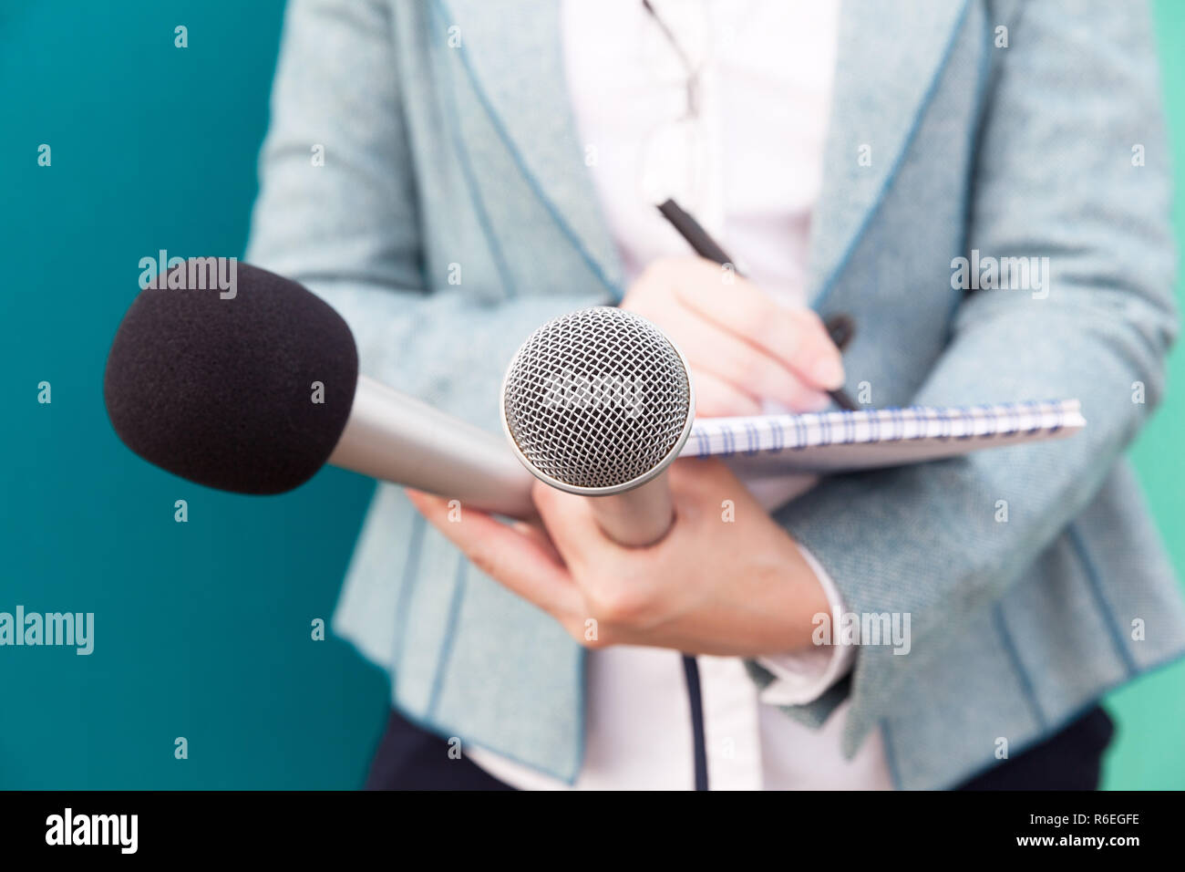 Giornalista In conferenza stampa, scrivere note, tenendo il microfono Foto Stock