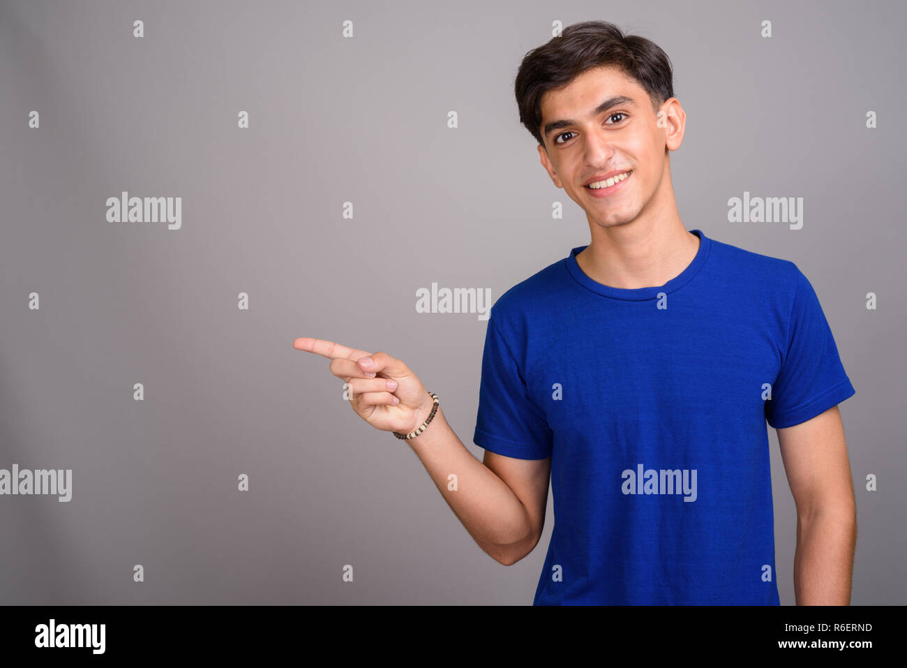 Giovani persiano bello ragazzo adolescente puntare il dito e mostrando copyspace Foto Stock