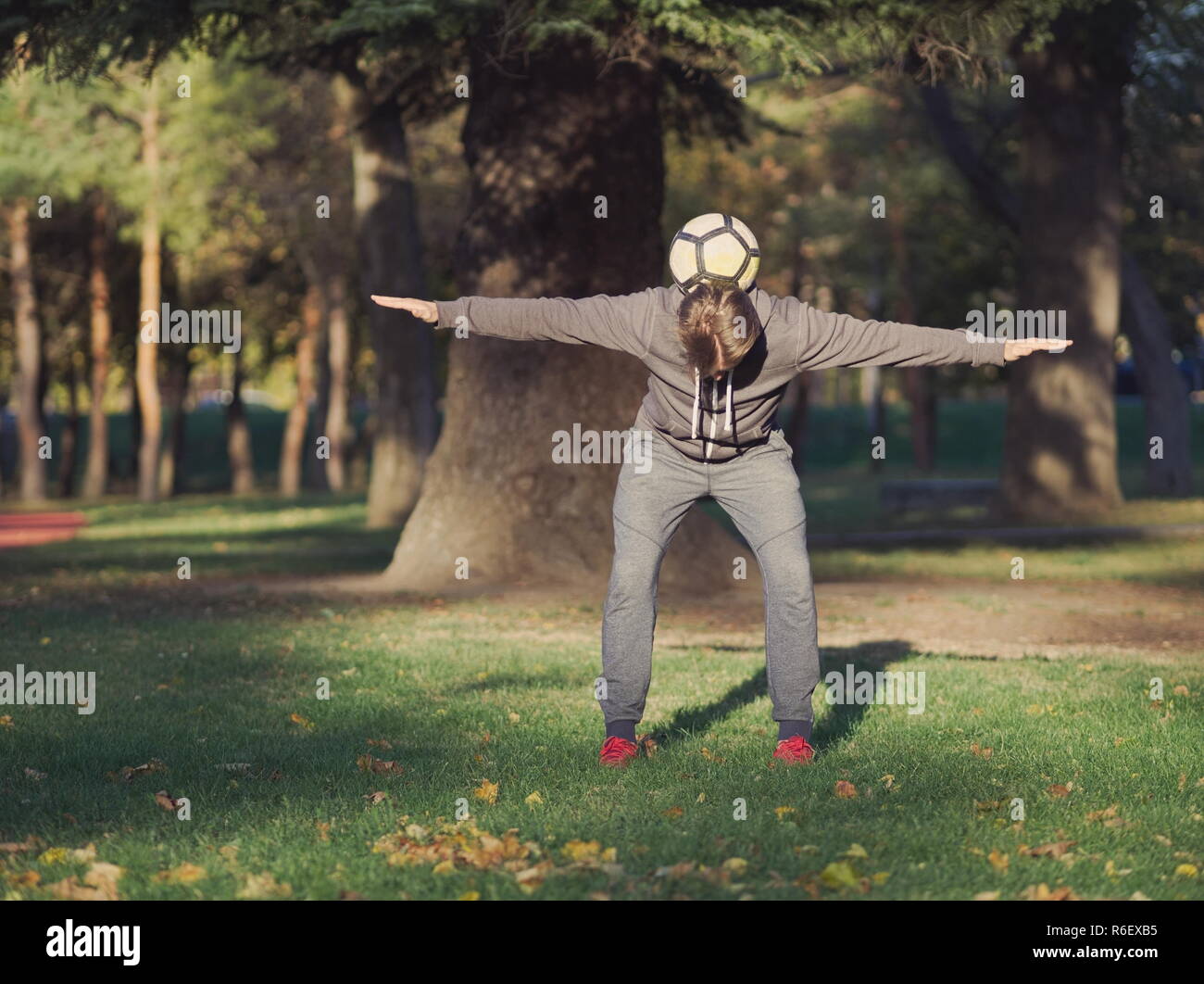 Giocatore di calcio Calcio di bilanciamento nel parco su una soleggiata giornata autunnale Foto Stock