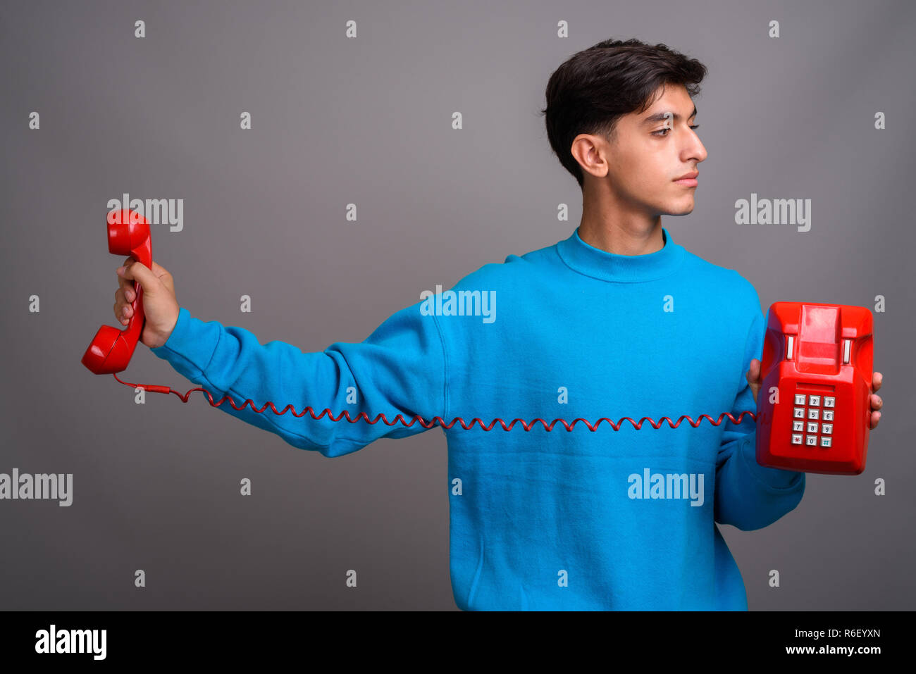 Giovani persiano bello ragazzo adolescente parlando su rosso vecchio telefono Foto Stock