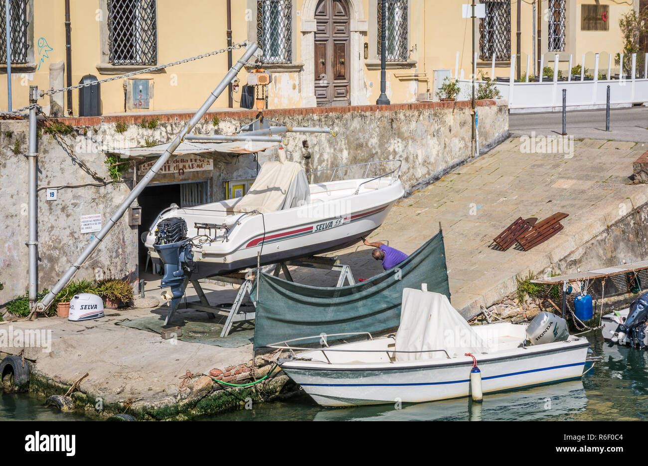 L'uomo ripristino vintage in legno barca a remi nel quartiere Venezia di Livorno, Toscana, Italia Foto Stock