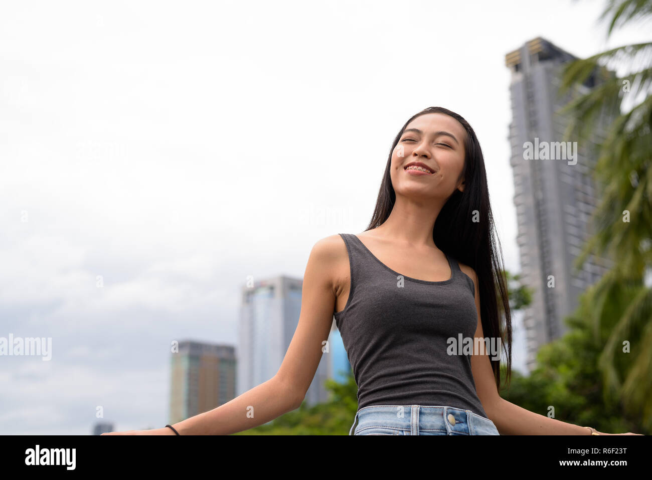 Felice giovane bella donna asiatica di relax presso il parco con gli occhi chiusi Foto Stock