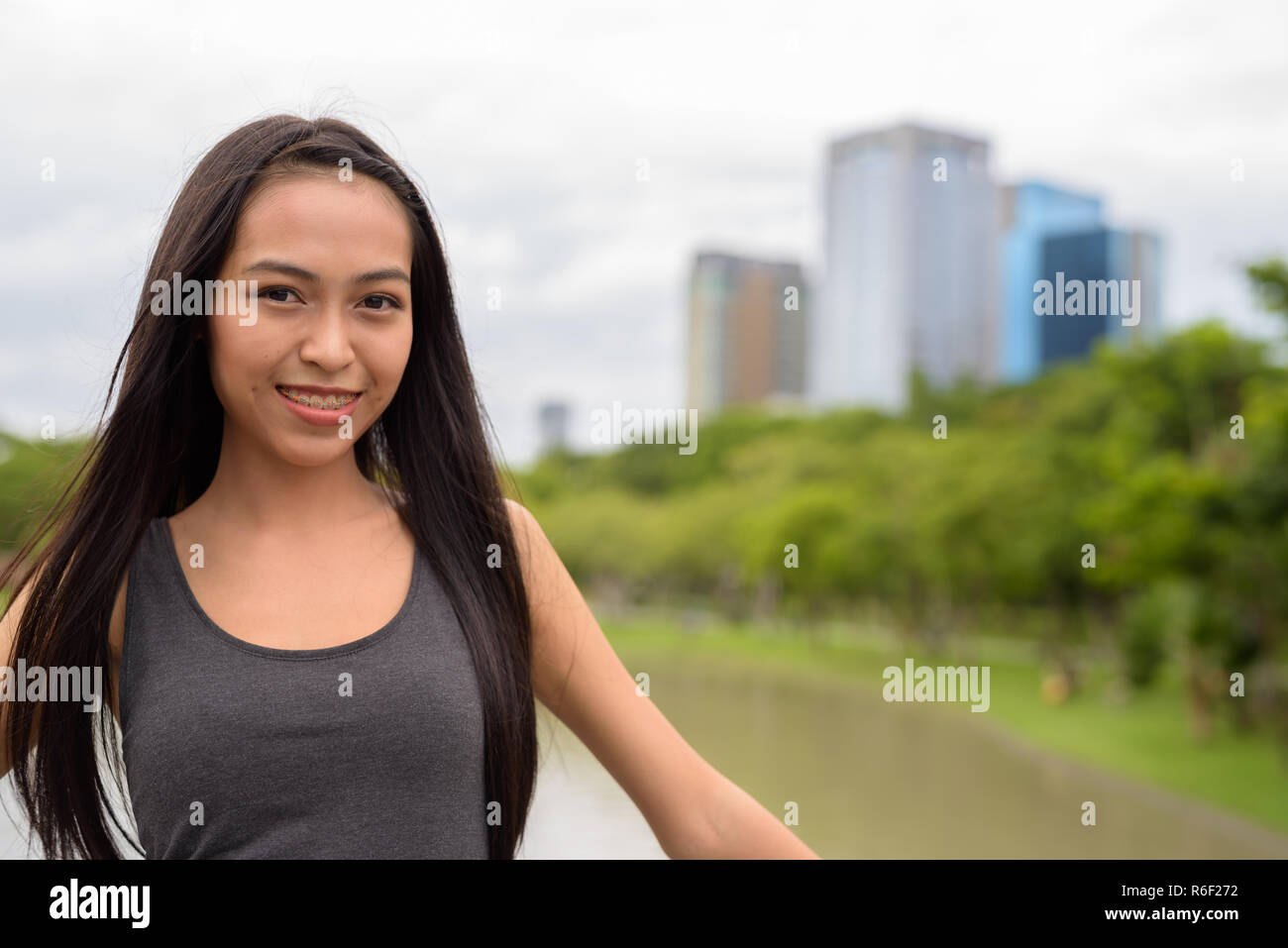 Felice giovane bella donna asiatica sorridente e relax presso il parco Foto Stock